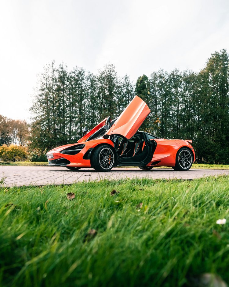 Außergewöhnliche Veranstaltungen im Jagdhof Oranger Sportwagen mit geöffneten Schmetterlingstüren auf Parkfläche vor Bäumen