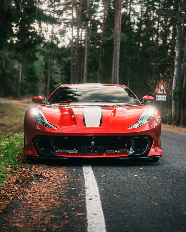 Außergewöhnliche Veranstaltungen im Jagdhof Rotes Sportauto mit weißen Streifen auf Waldstraße geparkt