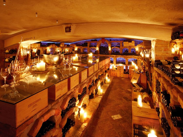 Außergewöhnliche Veranstaltungen im Jagdhof Weinkeller mit Weinflaschen, Kerzenlicht und Gläser auf einem Glastisch