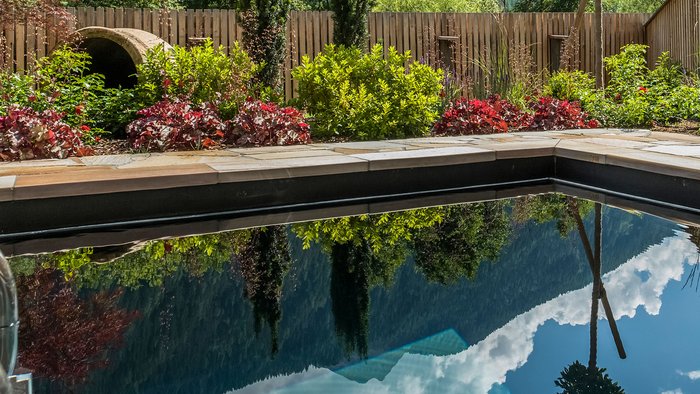 Wie es sich für ein 5-Sterne-Hotel gehört: die Angebote. Garten mit Teich und Bergblick unter bewölktem Himmel