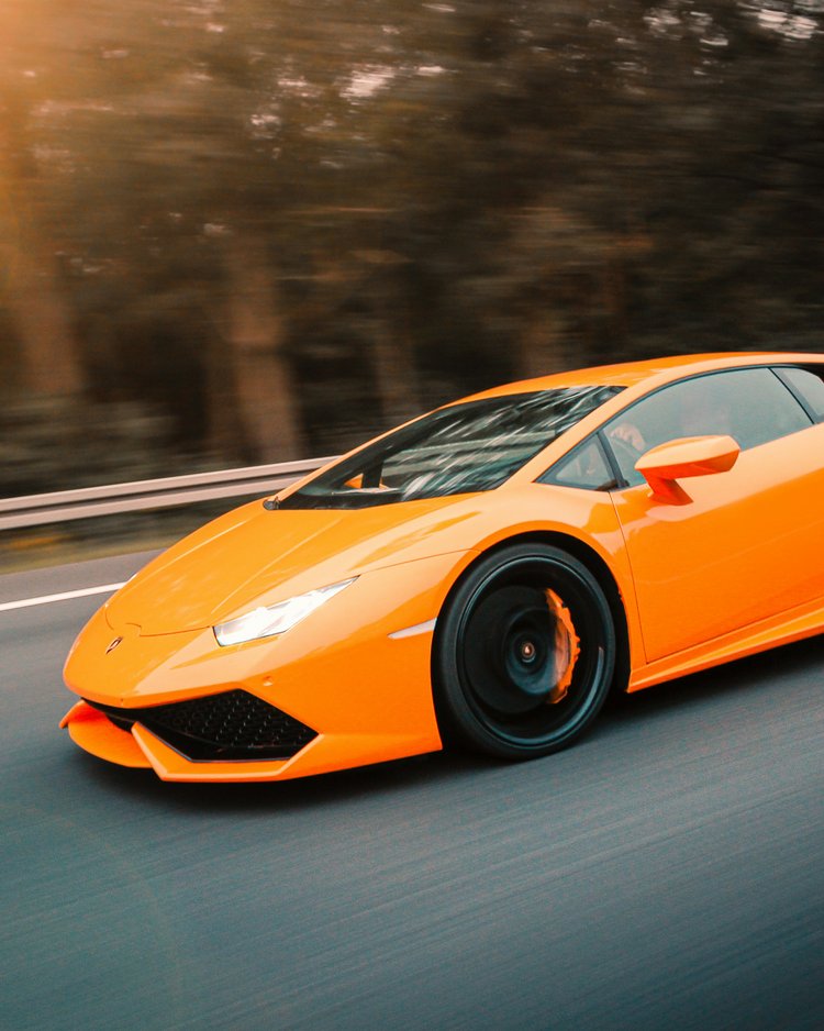 Außergewöhnliche Veranstaltungen im Jagdhof Oranger Sportwagen fährt auf der Straße bei Sonnenuntergang