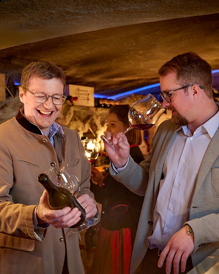 Außergewöhnliche Veranstaltungen im Jagdhof Zwei Männer probieren Wein in einem gemütlichen Weinkeller
