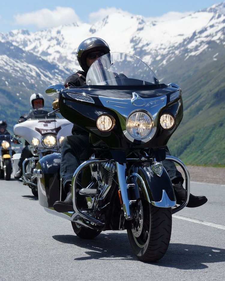 Außergewöhnliche Veranstaltungen im Jagdhof Gruppe von Motorradfahrern fährt auf Bergstraße mit schneebedeckten Gipfeln im Hintergrund