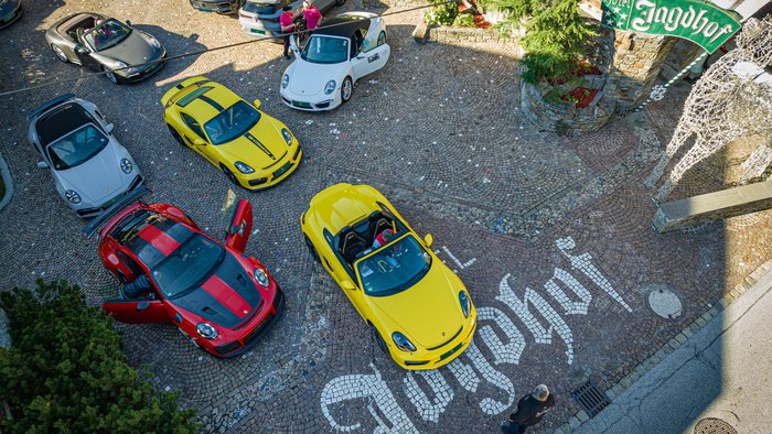 Wie es sich für ein 5-Sterne-Hotel gehört: die Angebote. Mehrere Sportwagen auf gepflastertem Hof mit Hotel Jagdhof Schriftzug