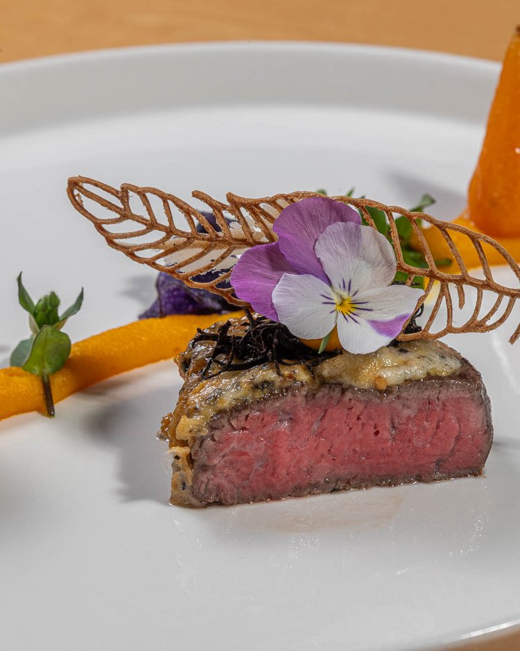 Außergewöhnliche Veranstaltungen im Jagdhof Gourmetgericht mit rosa gebratenem Fleisch, essbaren Blumen und feiner Dekoration