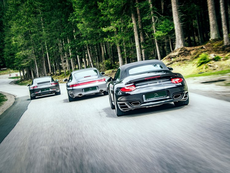 A highlight of the Jagdhof calendar: the Porsche Meetup Three sports cars driving on a winding forest road