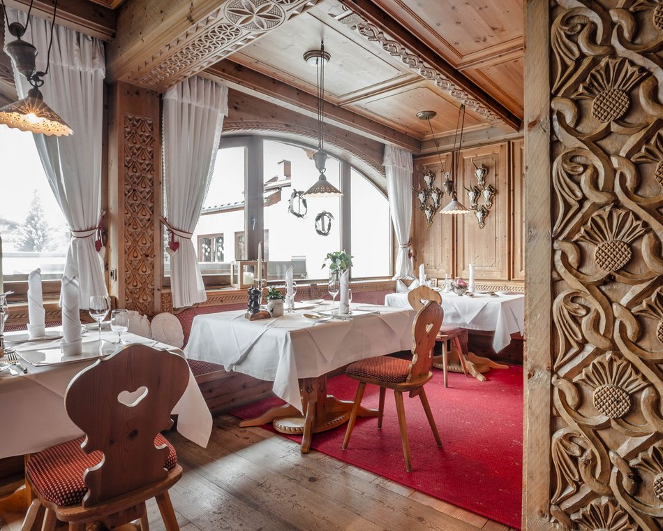 Willkommen im einzigen 5-Sterne-Hotel im Stubaital! Gemütlicher Holzrestaurantbereich mit geschnitzten Wänden und weiß gedeckten Tischen