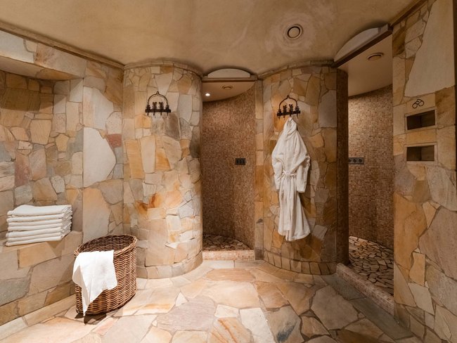 Auf in Ihr De-luxe-Wellnesshotel im Stubaital Steinverkleidete Dusche mit Bademantel und Handtüchern im Spa-Bereich