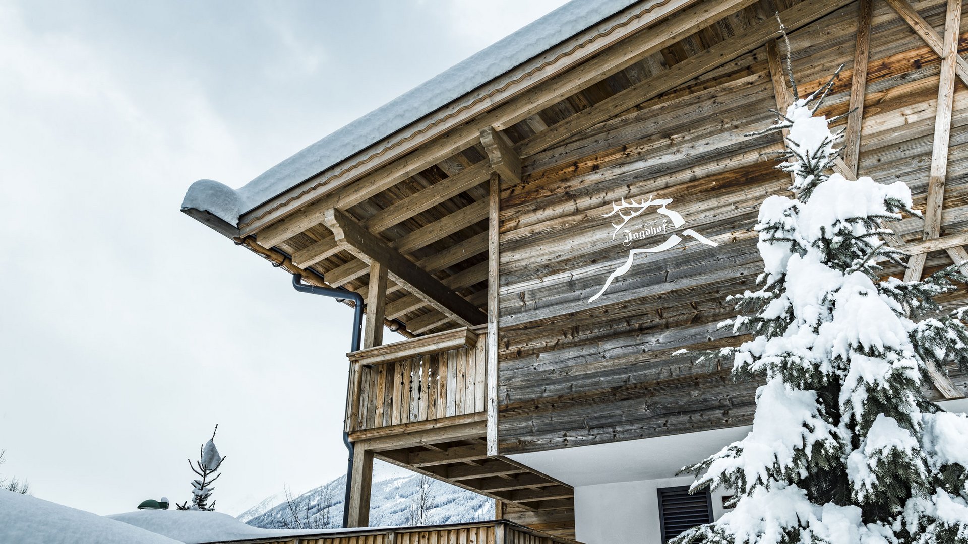 Willkommen im einzigen 5-Sterne-Hotel im Stubaital! Verschneites Holzhaus mit Garten und Tannenbaum im Winter