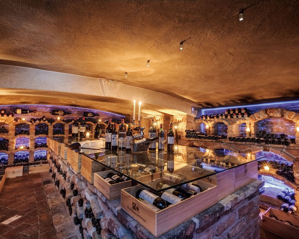 Willkommen im einzigen 5-Sterne-Hotel im Stubaital! Weinkeller mit Weinflaschen, Kerzenlicht und Steinwänden