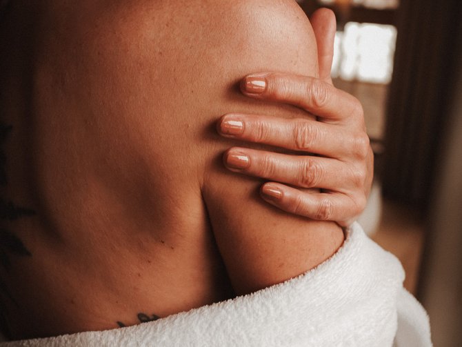 Lo Jagdhof: una scelta eccellente Donna con accappatoio bianco che si tocca la spalla in ambiente interno