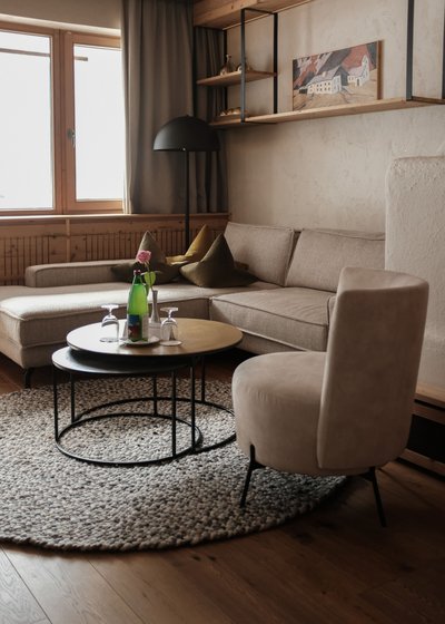 Willkommen im einzigen 5-Sterne-Hotel im Stubaital! Gemütliches Wohnzimmer mit Sofa, Sessel, zwei Tischen und Fenster