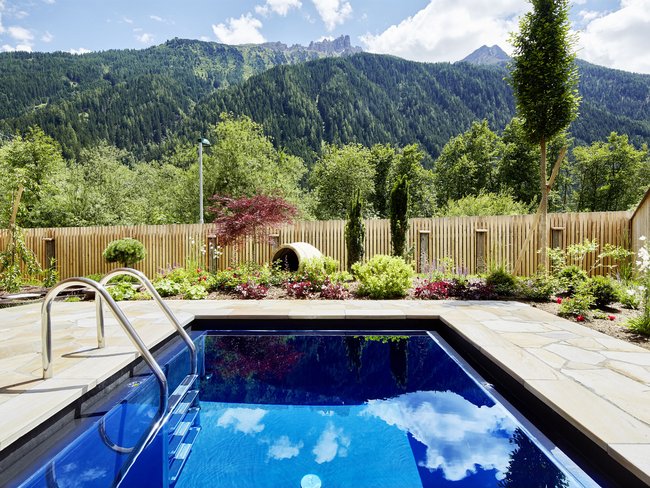 Auf in Ihr De-luxe-Wellnesshotel im Stubaital Kleiner Pool im Garten mit Bergblick und Blumenbeeten
