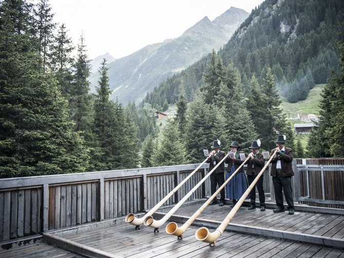 Natura, tradizioni e attrazioni vicino allo Jagdhof Quattro musicisti suonano corni alpini su una terrazza di legno in montagna