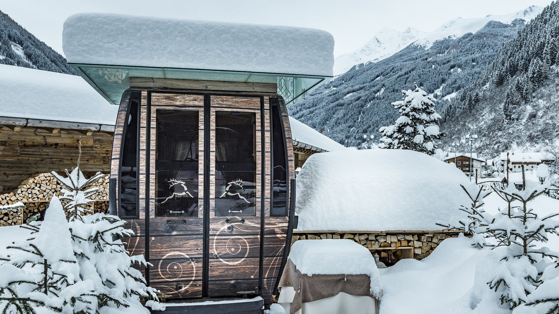 The Fondue Gondola: a unique experience at the Jagdhof Snow-covered wooden cabin and tables in a winter mountain landscape