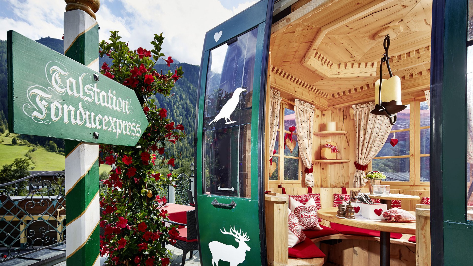 The Fondue Gondola: a unique experience at the Jagdhof Cozy wooden chalet with seating area and green alpine-style sign