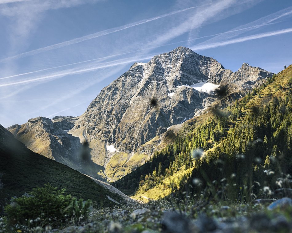 Willkommen im einzigen 5-Sterne-Hotel im Stubaital! Berglandschaft mit bewaldeten Hängen und felsigem Gipfel unter blauem Himmel