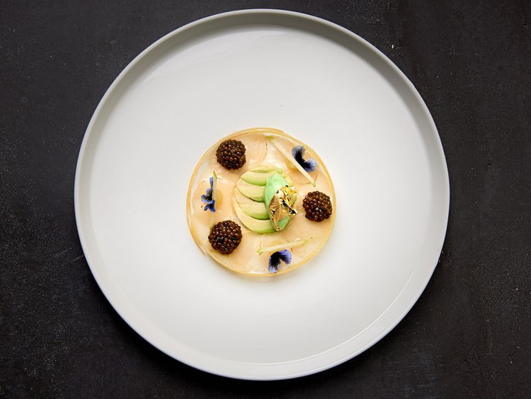Eines der besten Haubenrestaurants in Tirol Fein angerichtetes Gourmetgericht mit Perlen und essbaren Blumen auf weißem Teller