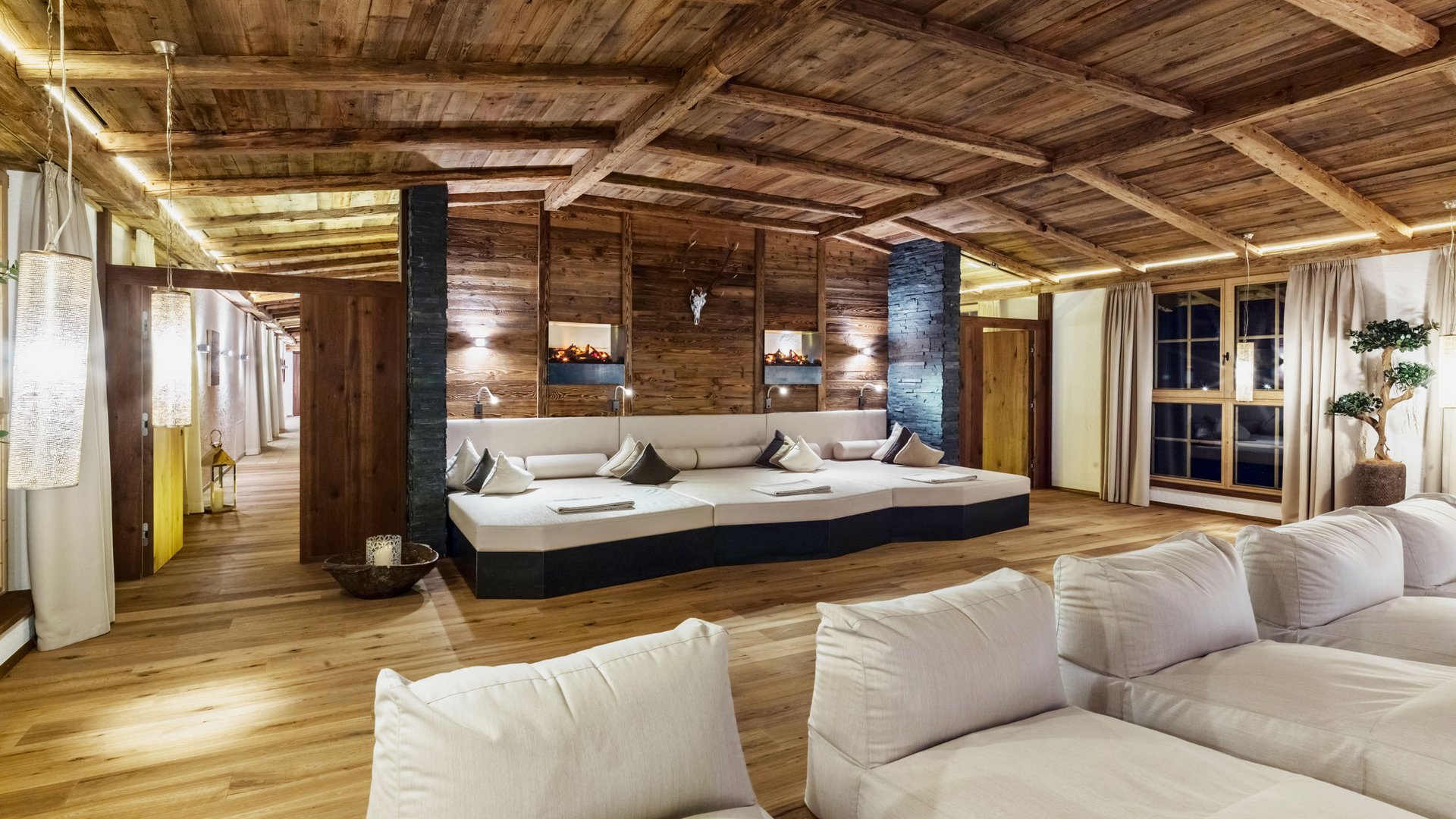 Willkommen im einzigen 5-Sterne-Hotel im Stubaital! Gemütlicher Raum mit Holzdecke, weißen Sofas und Kamin im modernen Alpenstil
