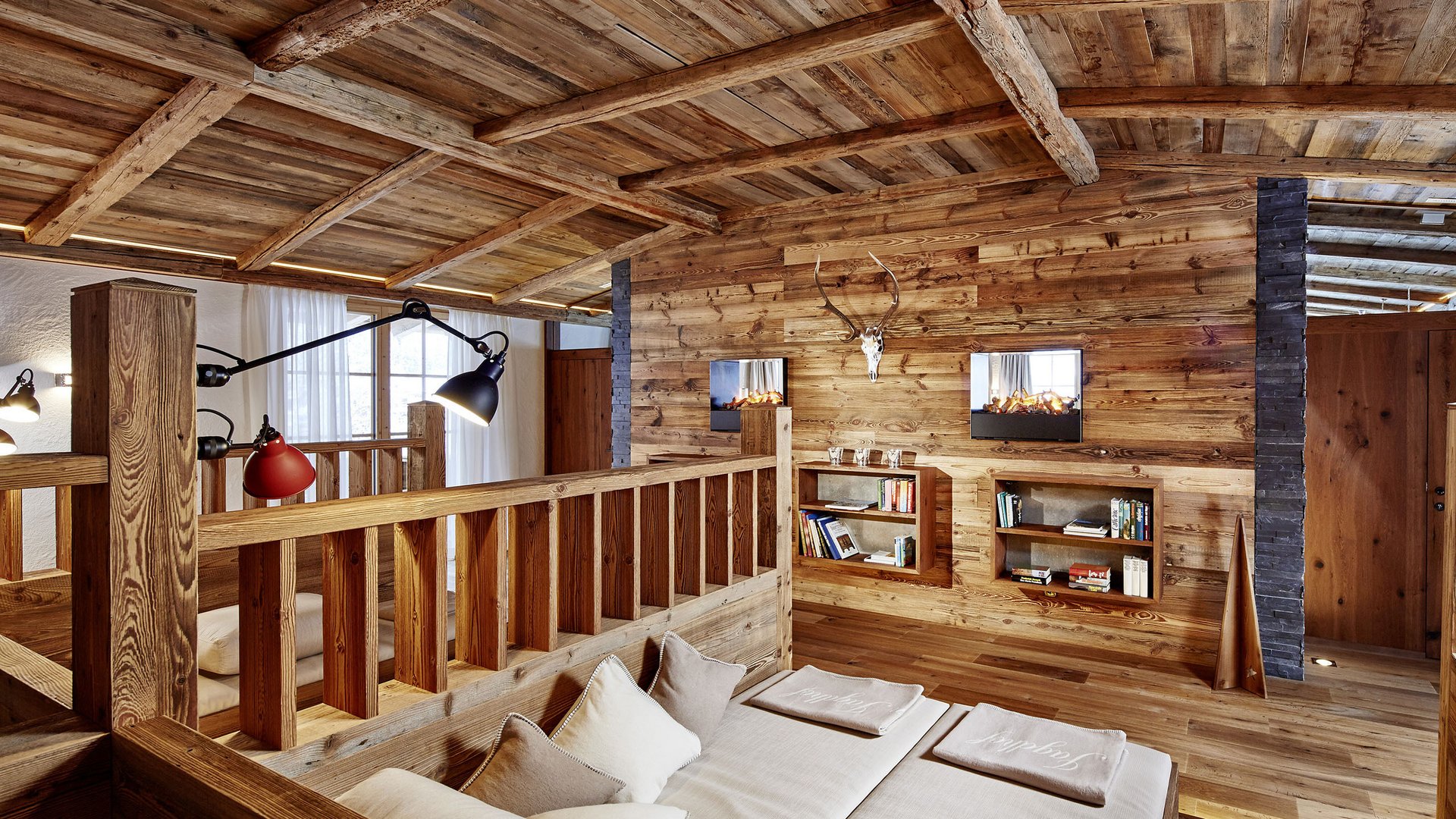 Willkommen im einzigen 5-Sterne-Hotel im Stubaital! Gemütlicher Holzinnenraum mit Kamin, Sofa und Bücherregal