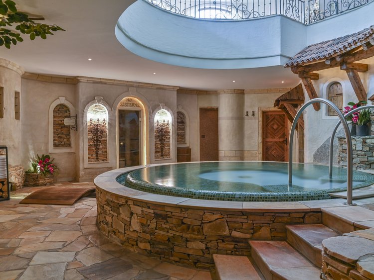 Auf in Ihr De-luxe-Wellnesshotel im Stubaital Rundes Spa-Becken mit Steinfassade in einem gemütlichen Innenraum