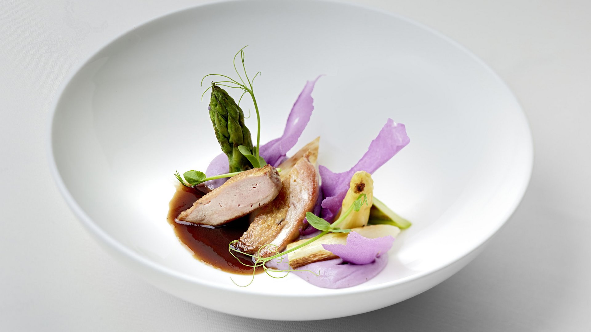 Willkommen im einzigen 5-Sterne-Hotel im Stubaital! Fein angerichtetes Gericht mit Spargel, Sauce, Fleisch und violetten Creme-Tupfen