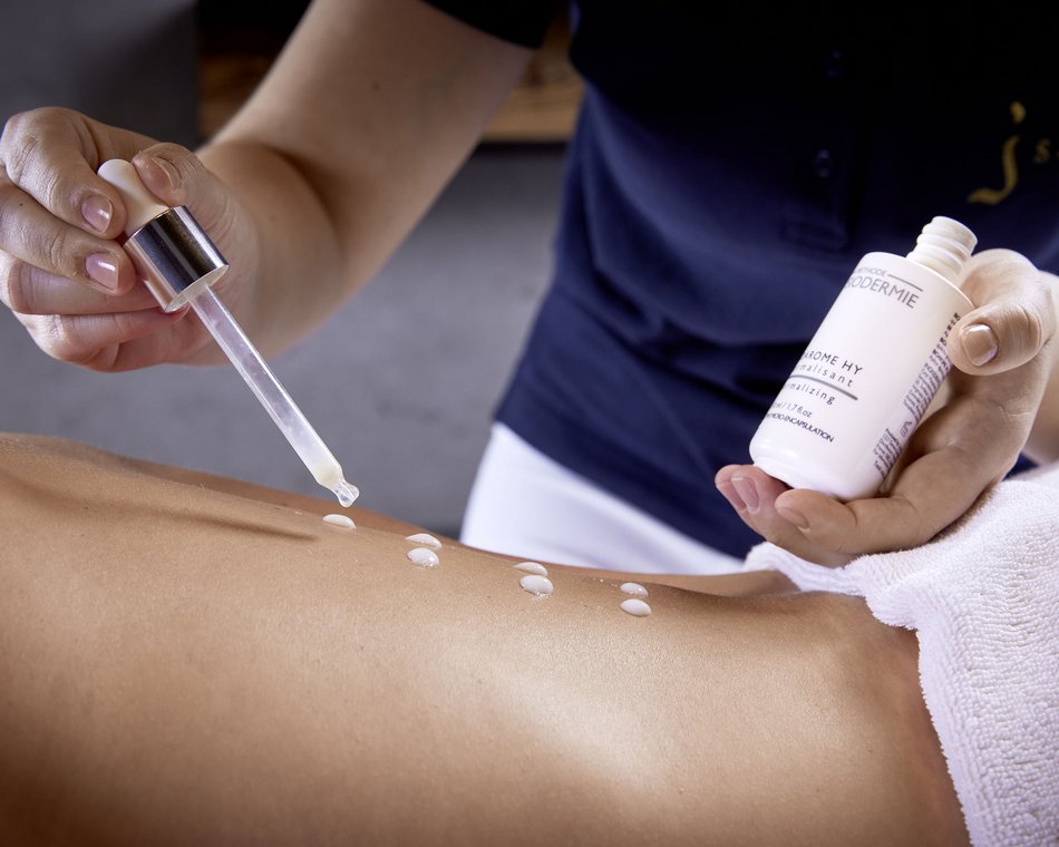 La suite con spa in camera più bella dell’Austria Operatore applica una lozione con pipetta sulla schiena nuda