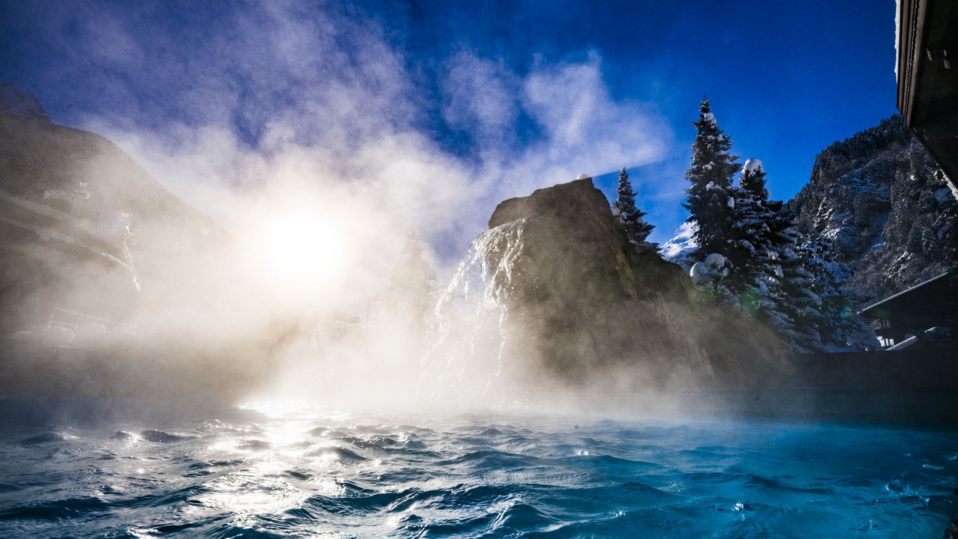 Willkommen im einzigen 5-Sterne-Hotel im Stubaital! Dampfendes Thermalwasser vor schneebedeckten Bergen und Bäumen bei Sonnenlicht