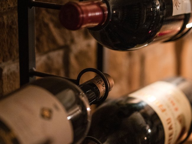 Willkommen im einzigen 5-Sterne-Hotel im Stubaital! Weinflaschen in einem Weinregal an einer Steinwand