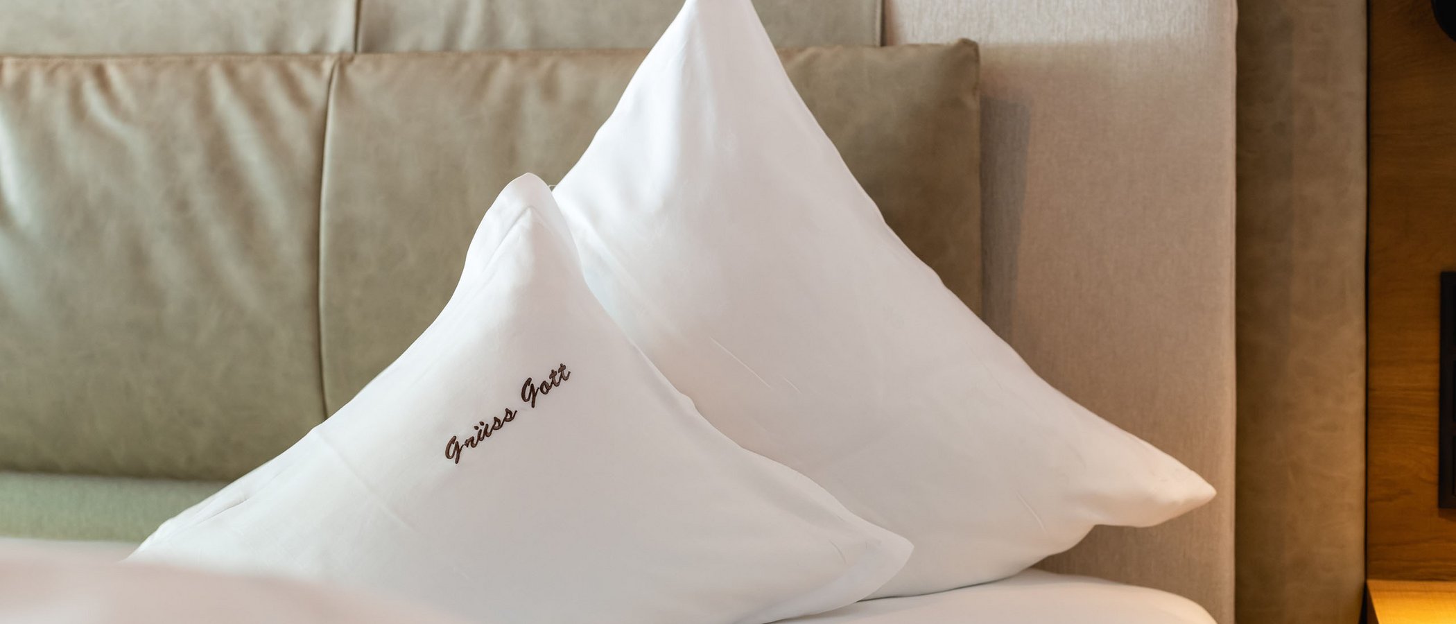Willkommen im einzigen 5-Sterne-Hotel im Stubaital! Zwei weiße Kissen auf einem Bett mit gepolstertem Kopfteil