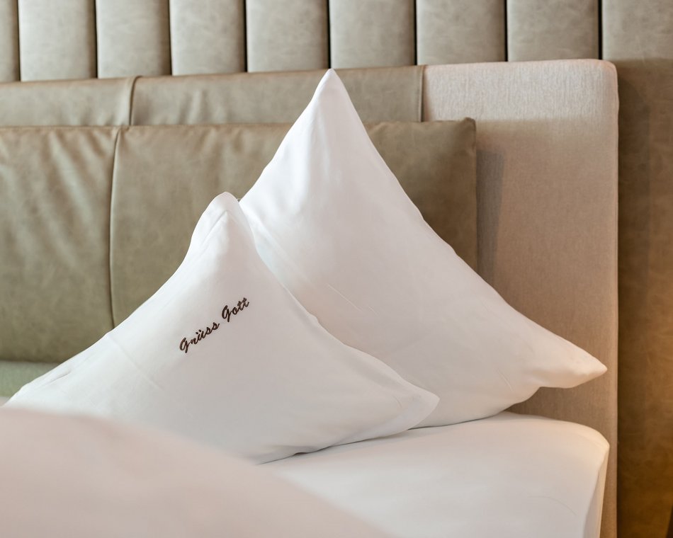 Willkommen im einzigen 5-Sterne-Hotel im Stubaital! Zwei weiße Kissen auf einem Bett mit gepolstertem Kopfteil