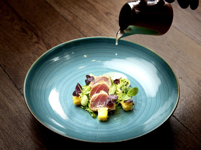 Willkommen im einzigen 5-Sterne-Hotel im Stubaital! Fein angerichtete Vorspeise mit rohem Fisch, Mango und Blattsalat auf blauem Teller