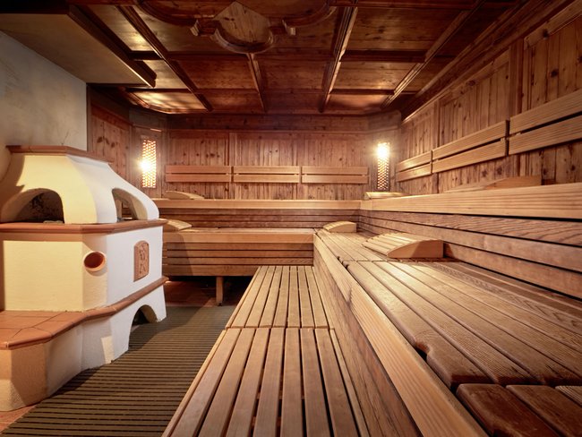 Auf in Ihr De-luxe-Wellnesshotel im Stubaital Gemütlicher Holzsauna mit warmem Licht und Ofen