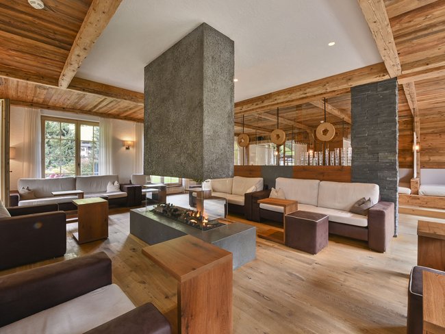 Willkommen im einzigen 5-Sterne-Hotel im Stubaital! Moderne Lounge mit Kamin, Holzmöbeln und gemütlichen Sofas