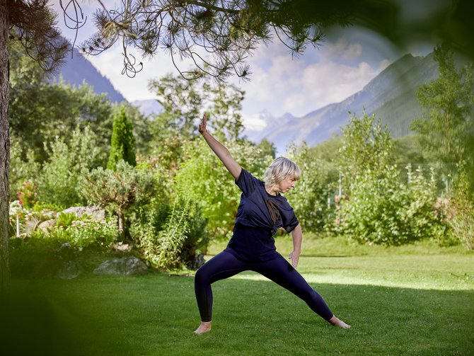 Yoga at our hotel in Tyrol Woman doing yoga in garden with mountain view on a sunny day