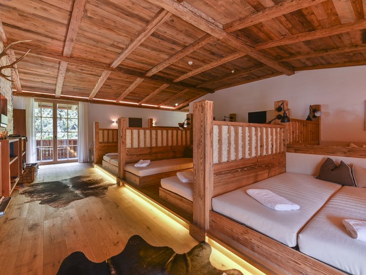 Auf in Ihr De-luxe-Wellnesshotel im Stubaital Rustikales Zimmer mit Holzbetten, Holzboden, Decke und gemütlichem Ambiente
