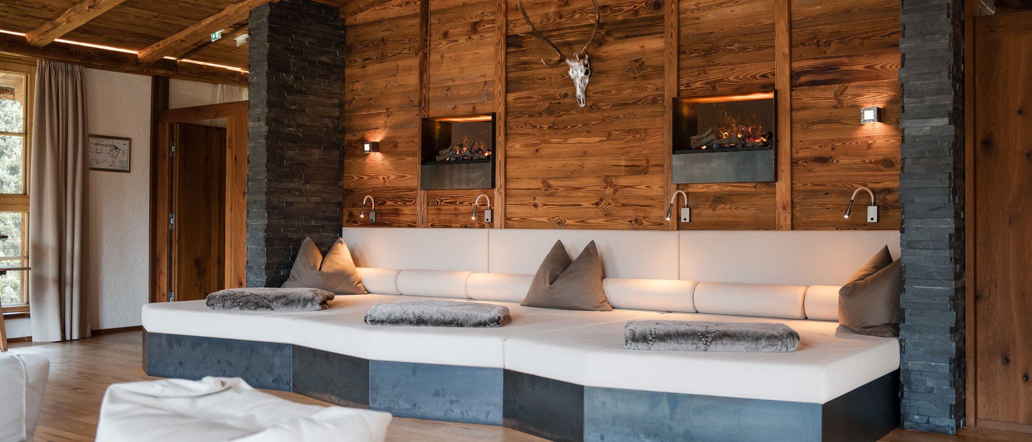 Willkommen im einzigen 5-Sterne-Hotel im Stubaital! Gemütliche Lounge mit Ledersofa und Hirschgeweih an Holzwand